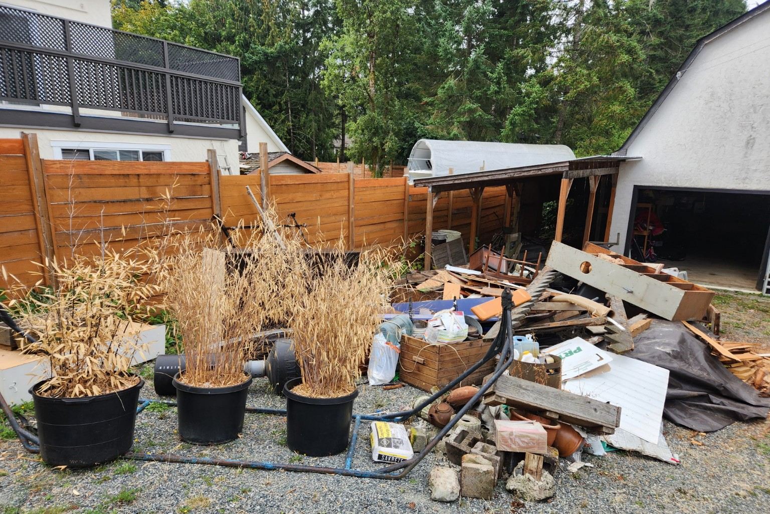 A large pile of wood and household debris beside a Nanaimo carport before a Junk Matters cleanup