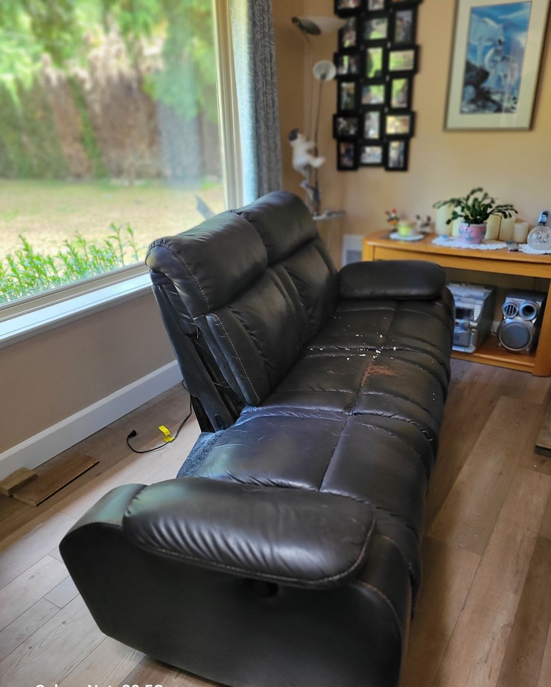 A large black leather reclining sectional filling a Nanaimo living room before Junk Matters removed it