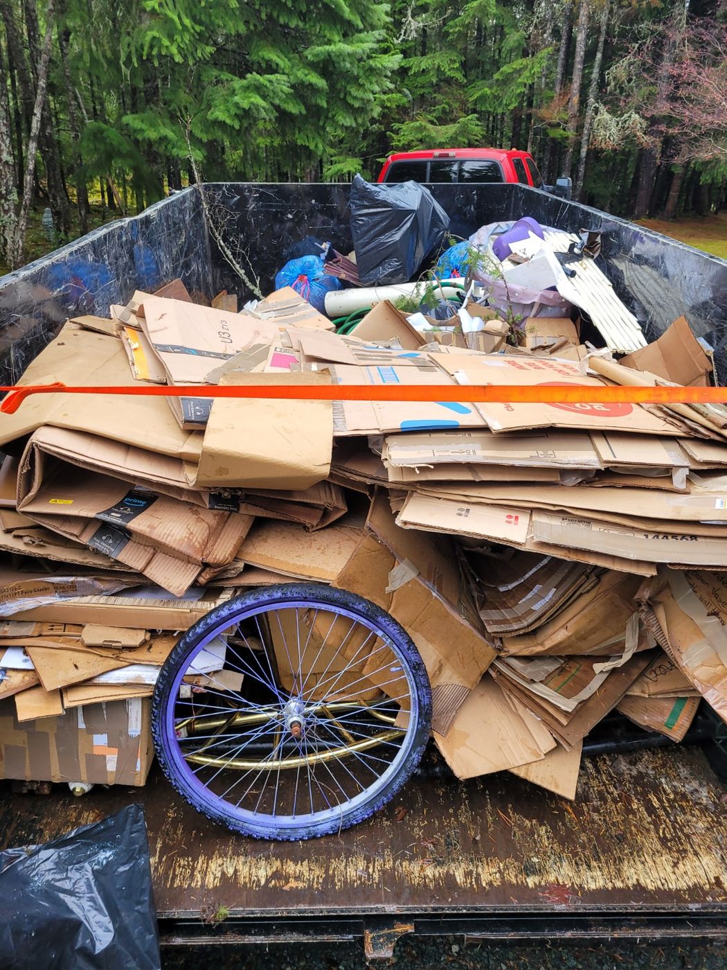 The Junk Matters trailer piled with flattened cardboard, packing material and a bicycle wheel in Nanaimo