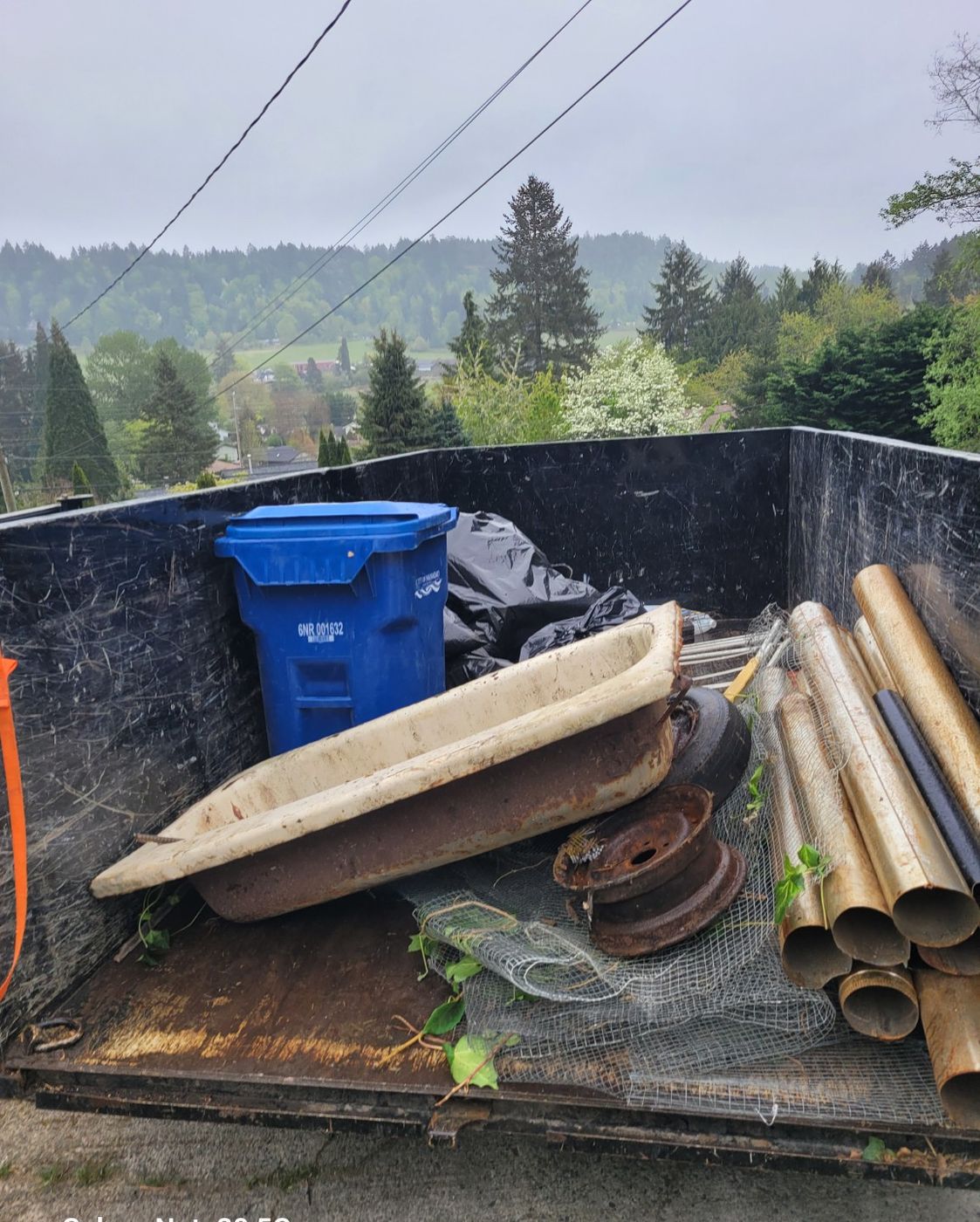 Lengths of metal pipe and a blue recycling bin loaded in the Junk Matters trailer in Nanaimo