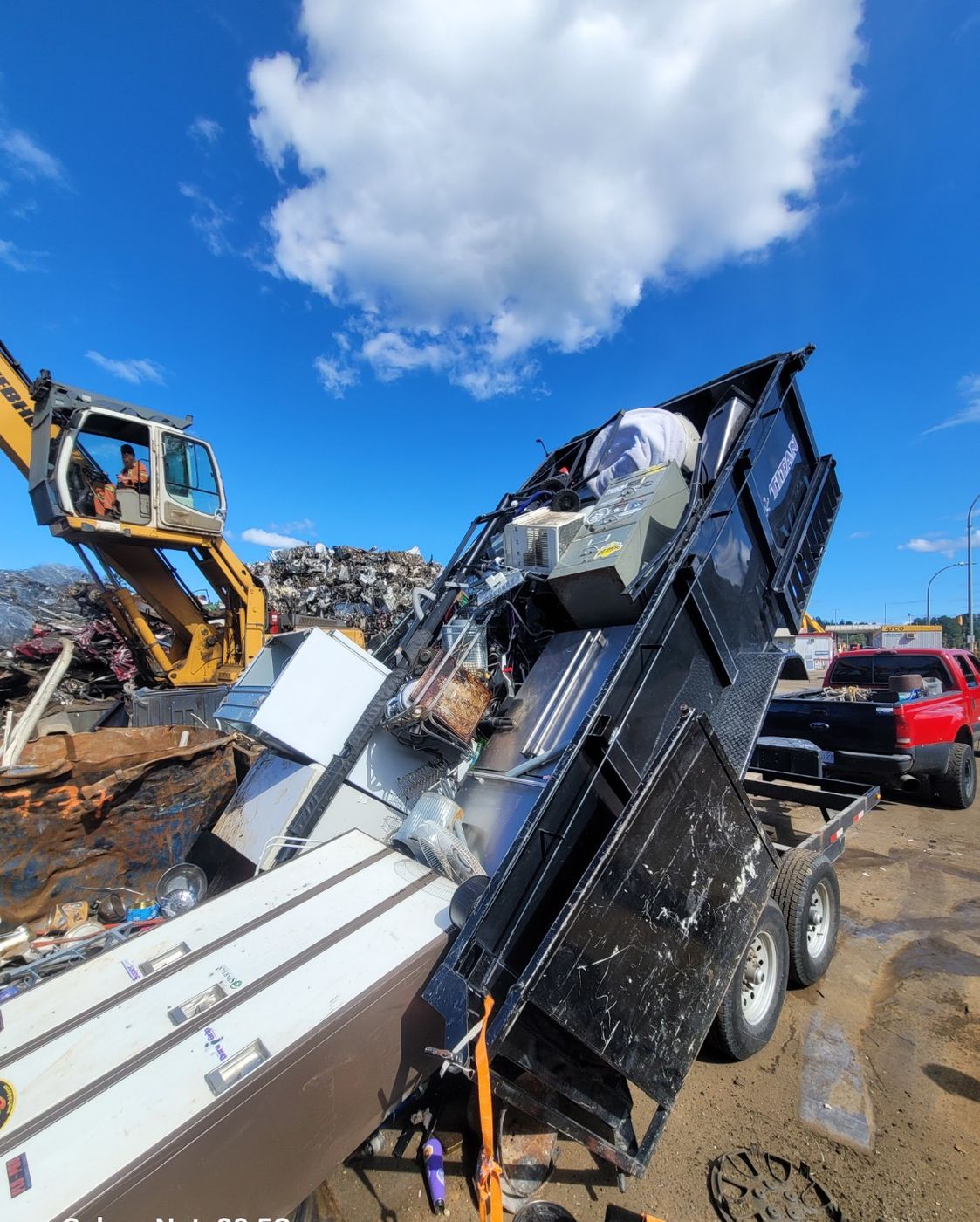 The Junk Matters trailer tipping scrap metal at the Nanaimo recycling yard while an excavator sorts the pile